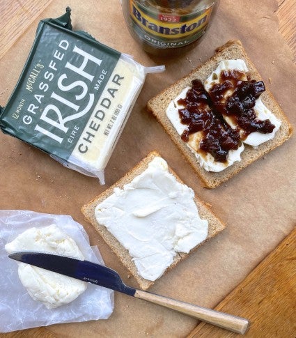 Grilled cheese sandwich being constructed from whole wheat bread, spreadable cheddar pub cheese, and Branston pickle.